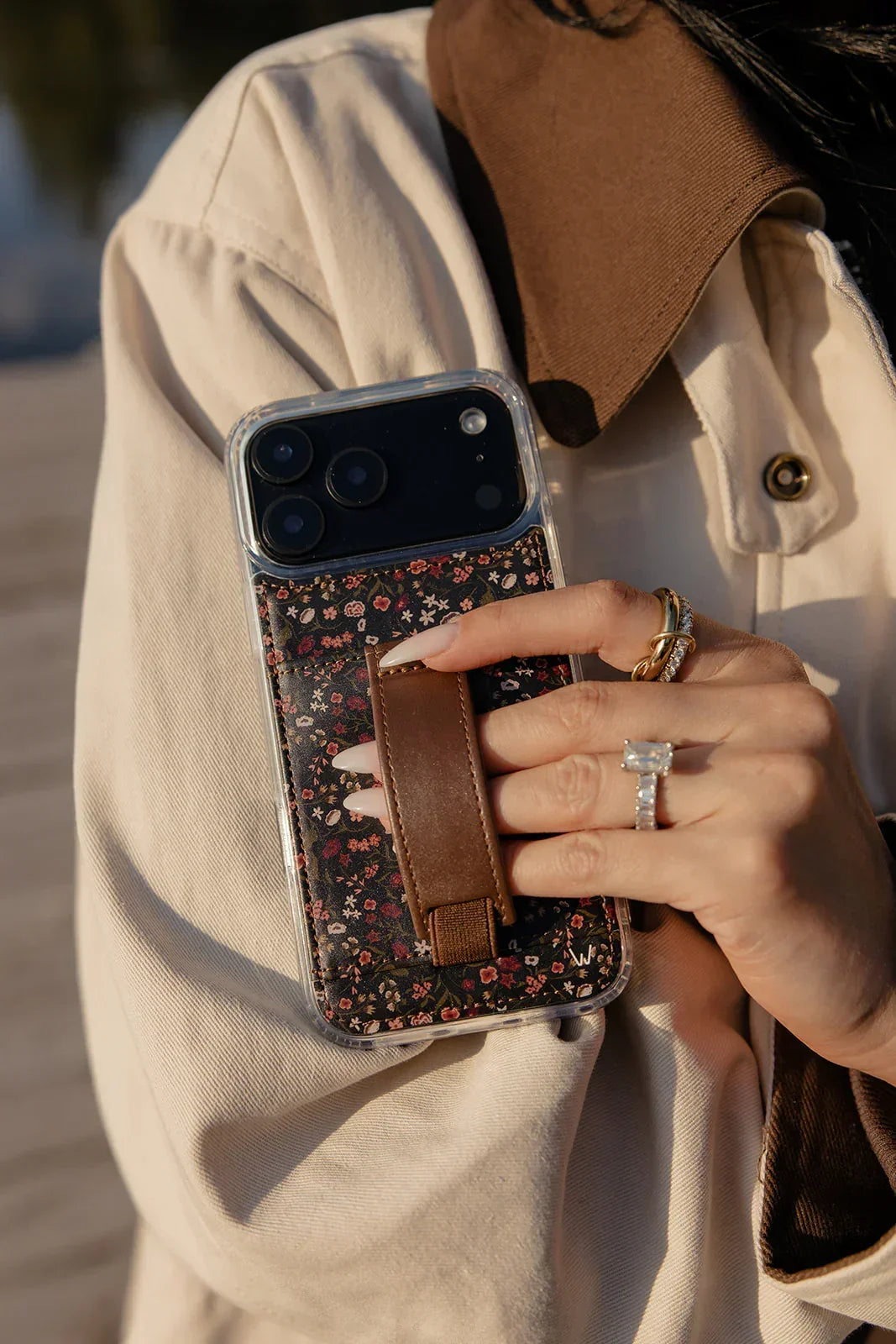 Close-up floral phone case with brown strap pocket and clear protective frame
