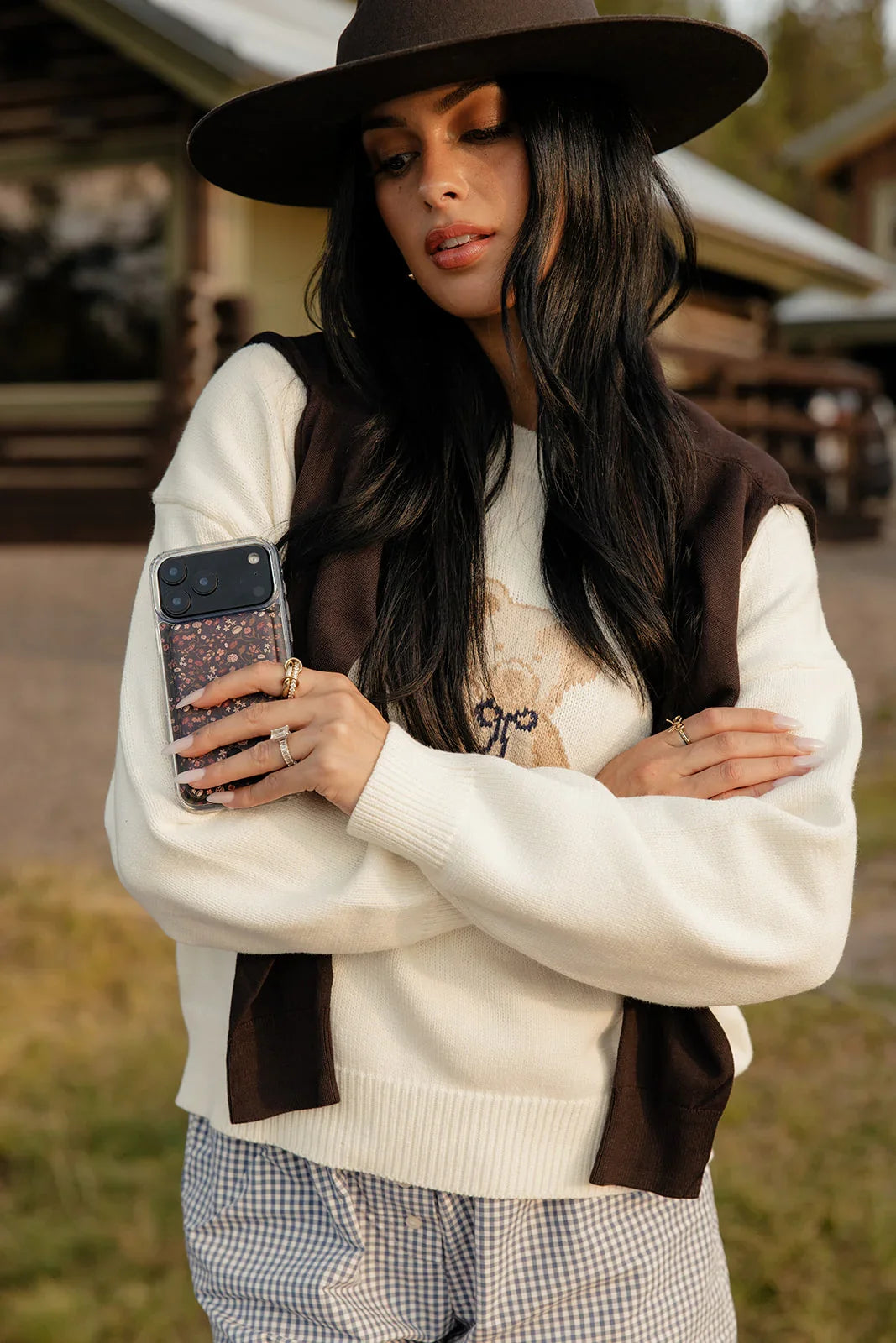 Dark floral phone case on smartphone held near chest