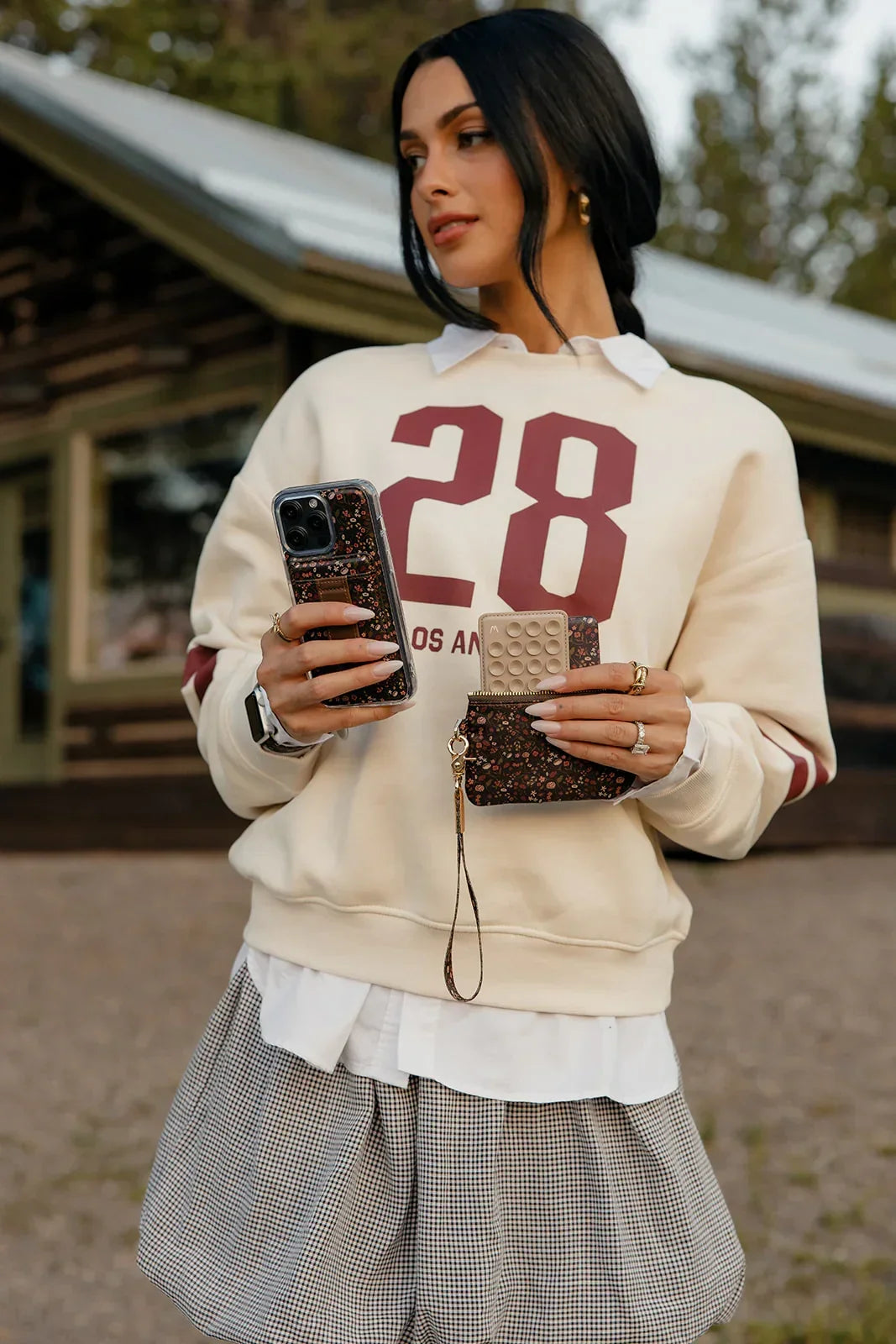 Floral phone case with brown strap pocket on a smartphone in hand