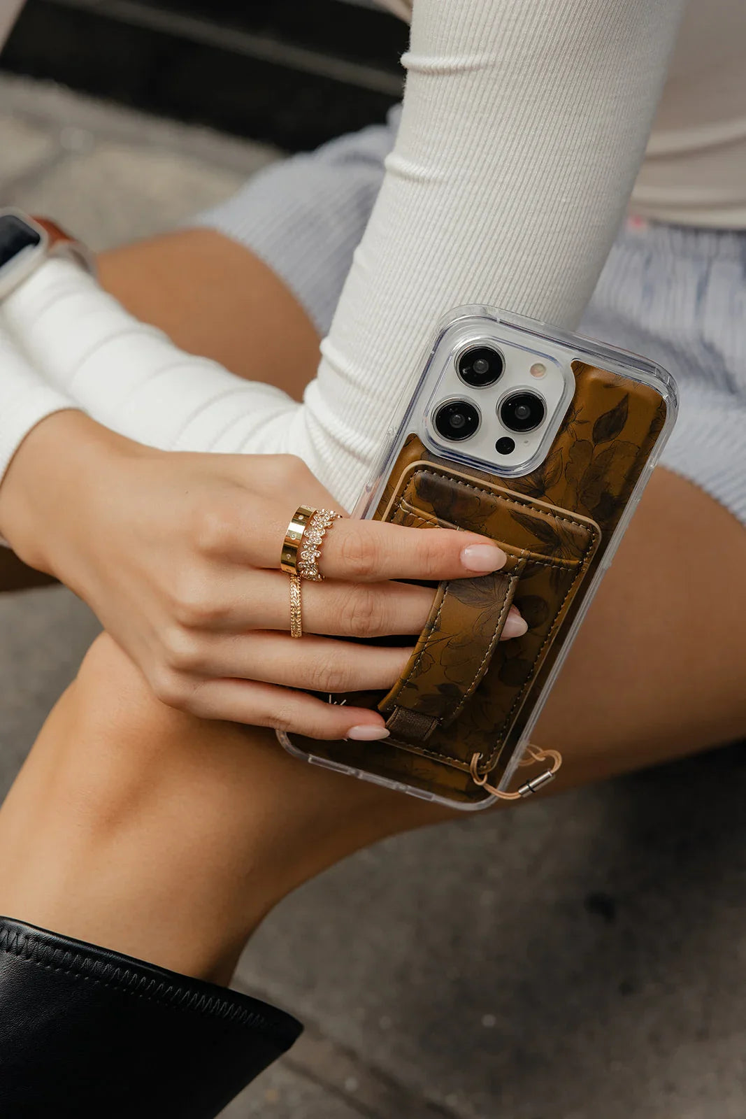 Brown magnetic wallet phone case with clear back, card pocket, and strap detail