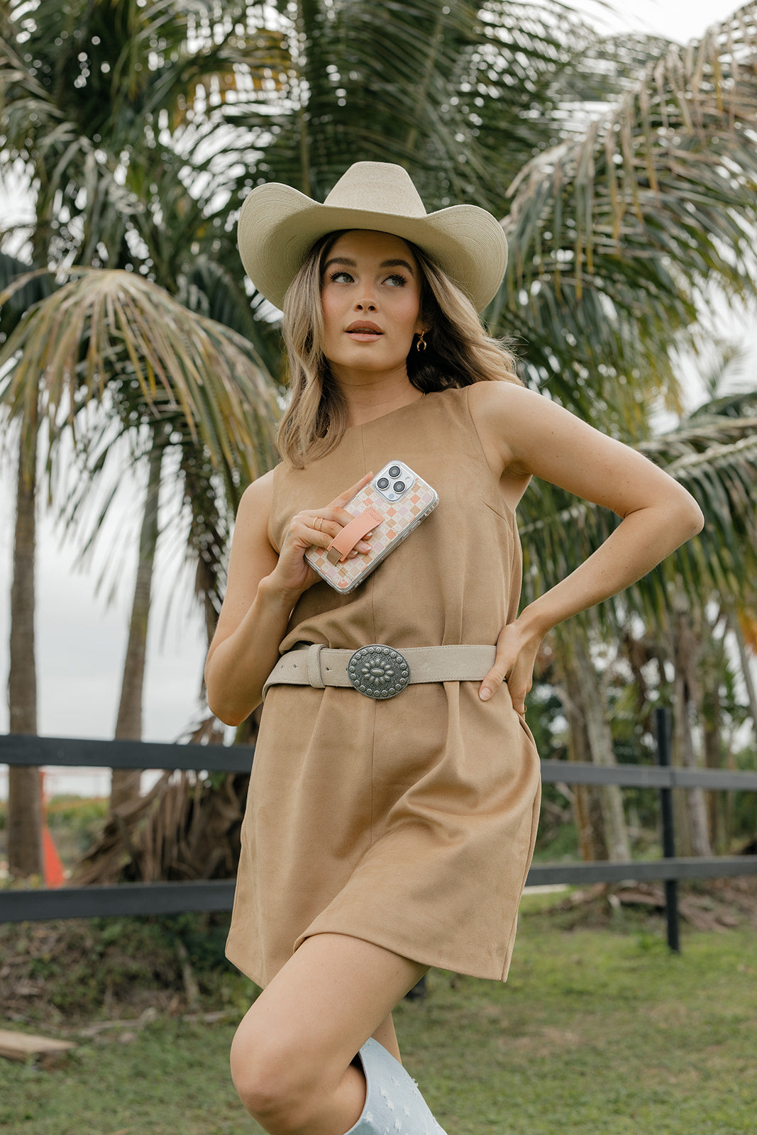 Peach bow patterned phone case with tan strap in hand with phone visible