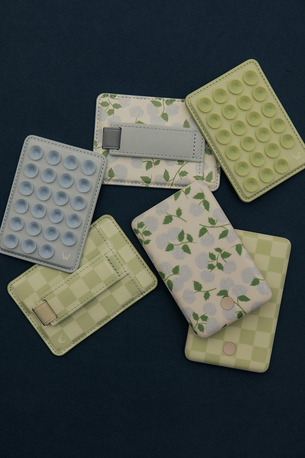 Cluster of floral magnetic wallets with gray strap closures and bubble-texture covers