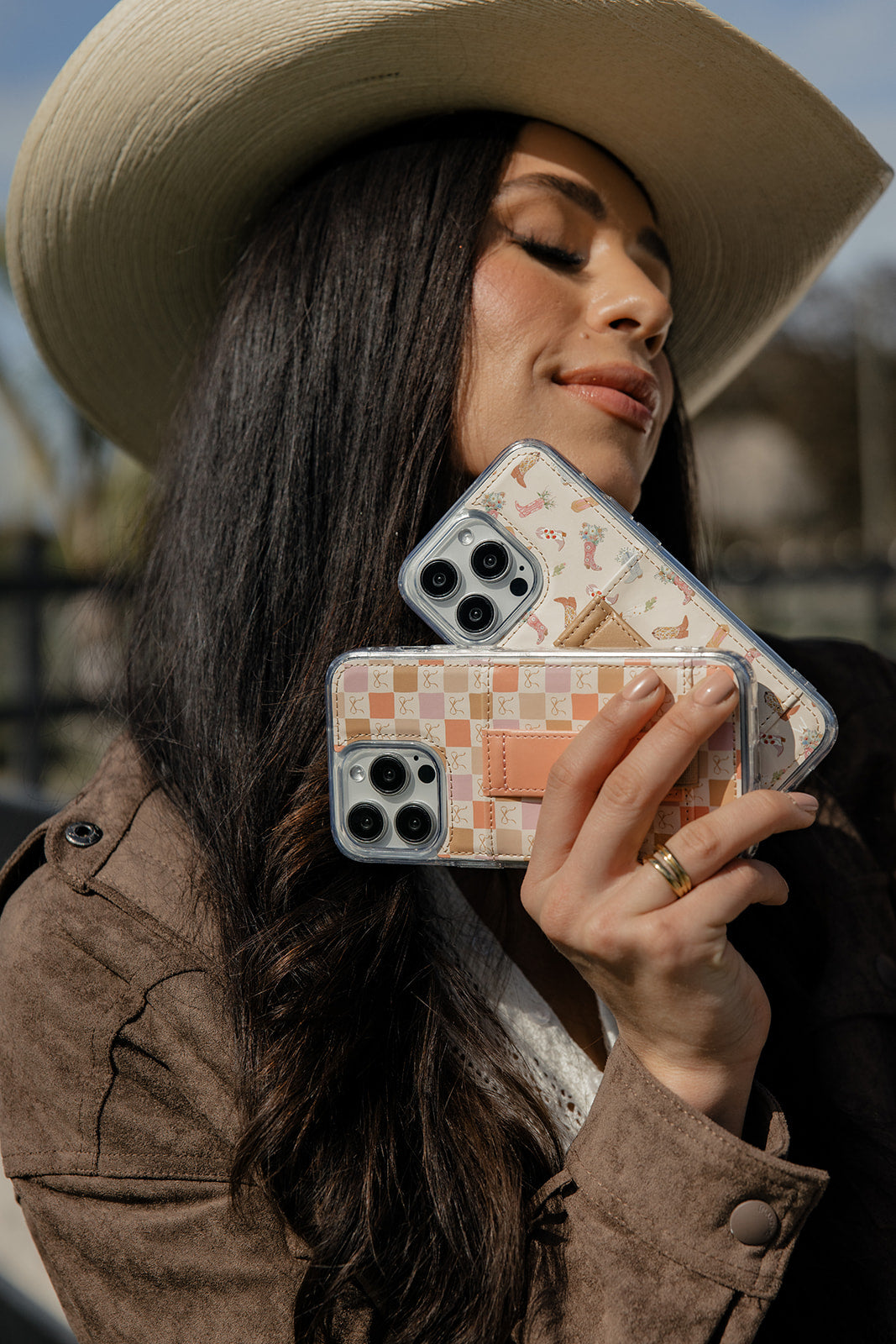 Orange-pink checker phone case with wrist strap, held in hand