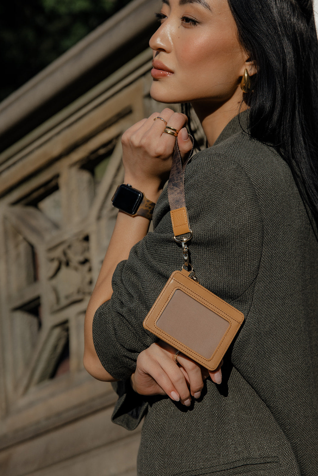 Wrist lanyard with tan square badge holder, attached to brown strap and gold clasp.