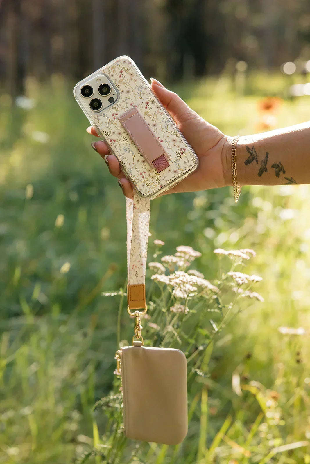 Floral wrist lanyard clipped to a phone with beige pouch and gold hardware