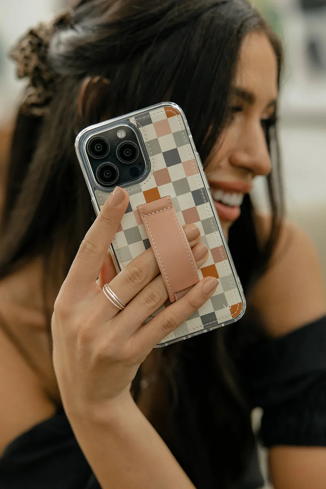 Check pattern phone case with tan strap, held toward camera