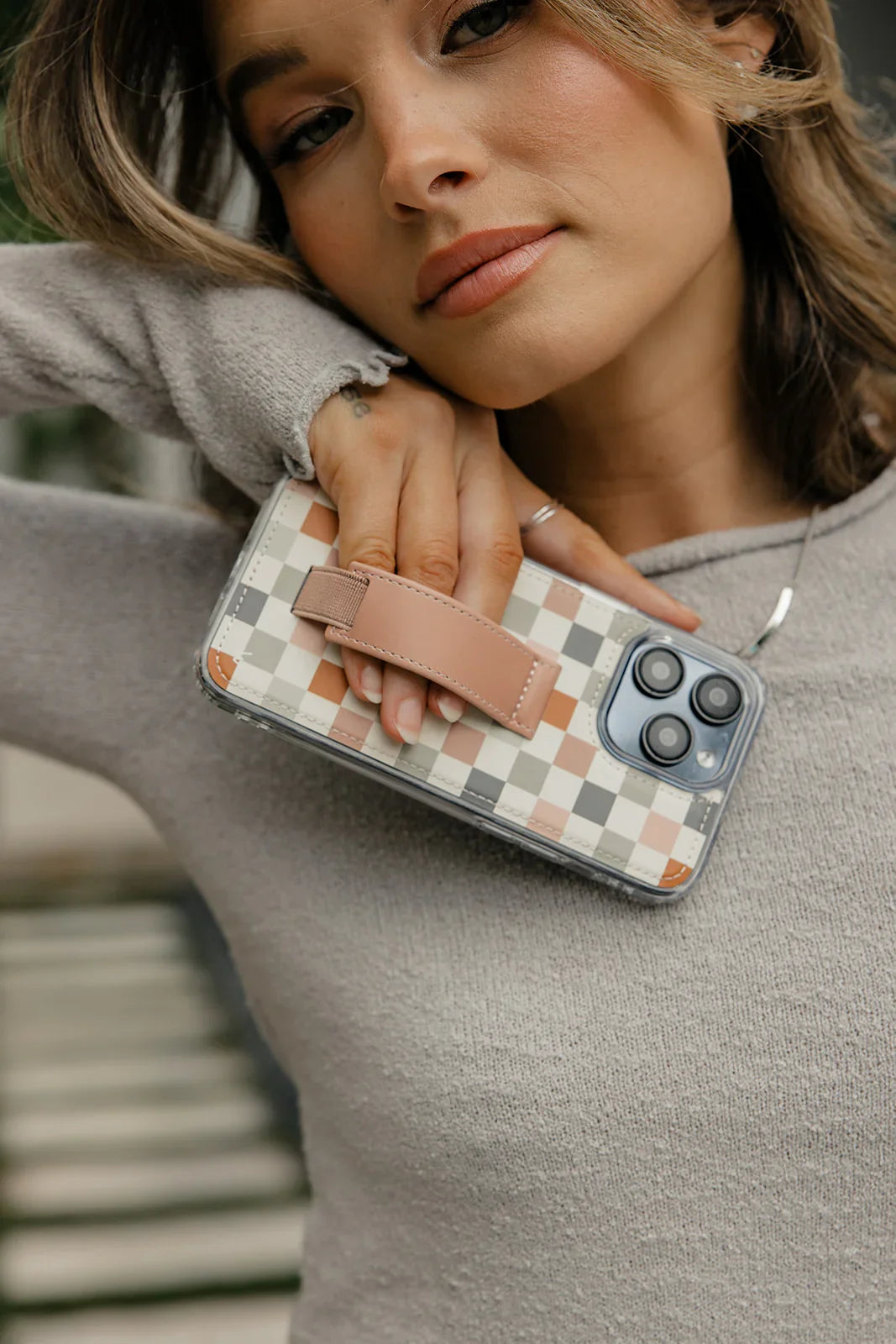 Check pattern Walli-Lite phone case with tan strap, held in hand