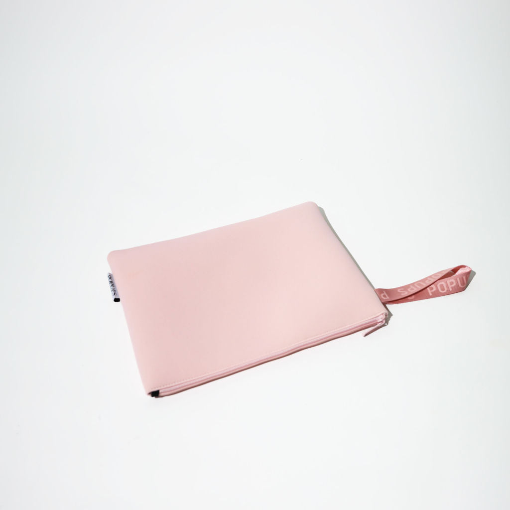 Pink zip laptop sleeve folded flat with ribbon strap extending from side