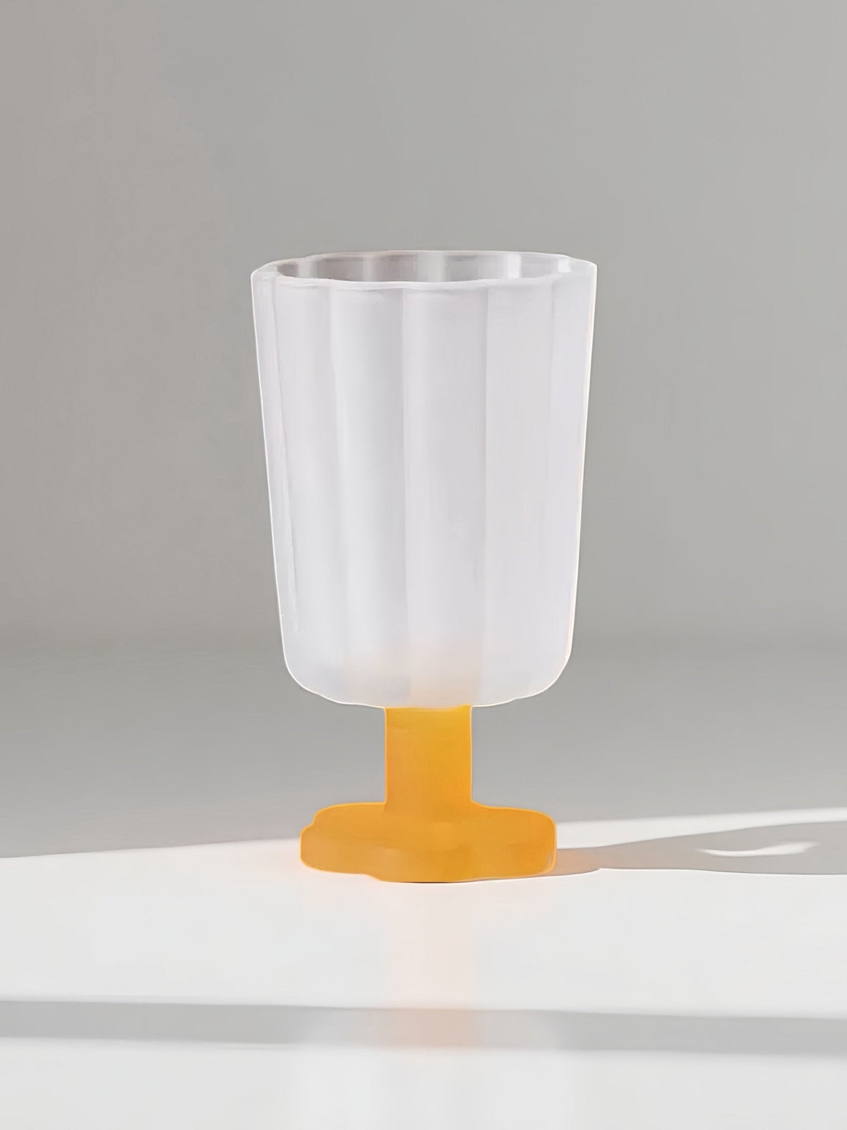 Hand-blown petal wine goblet with clear body and bright yellow base.