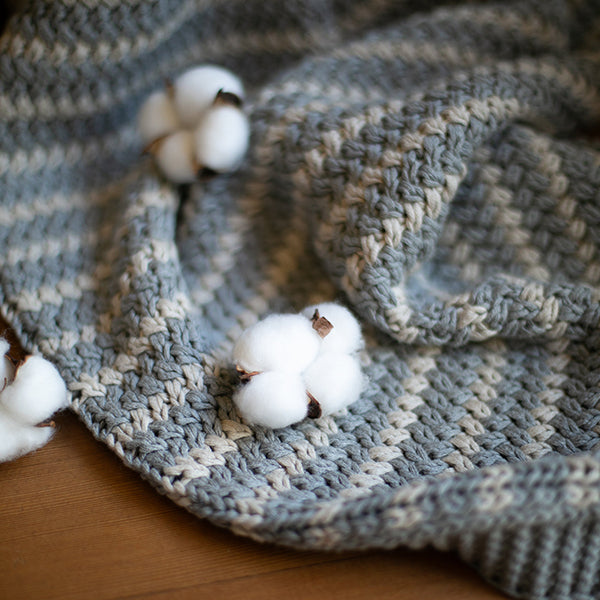Close-up of light gray chunky knit throw blanket with textured stitches