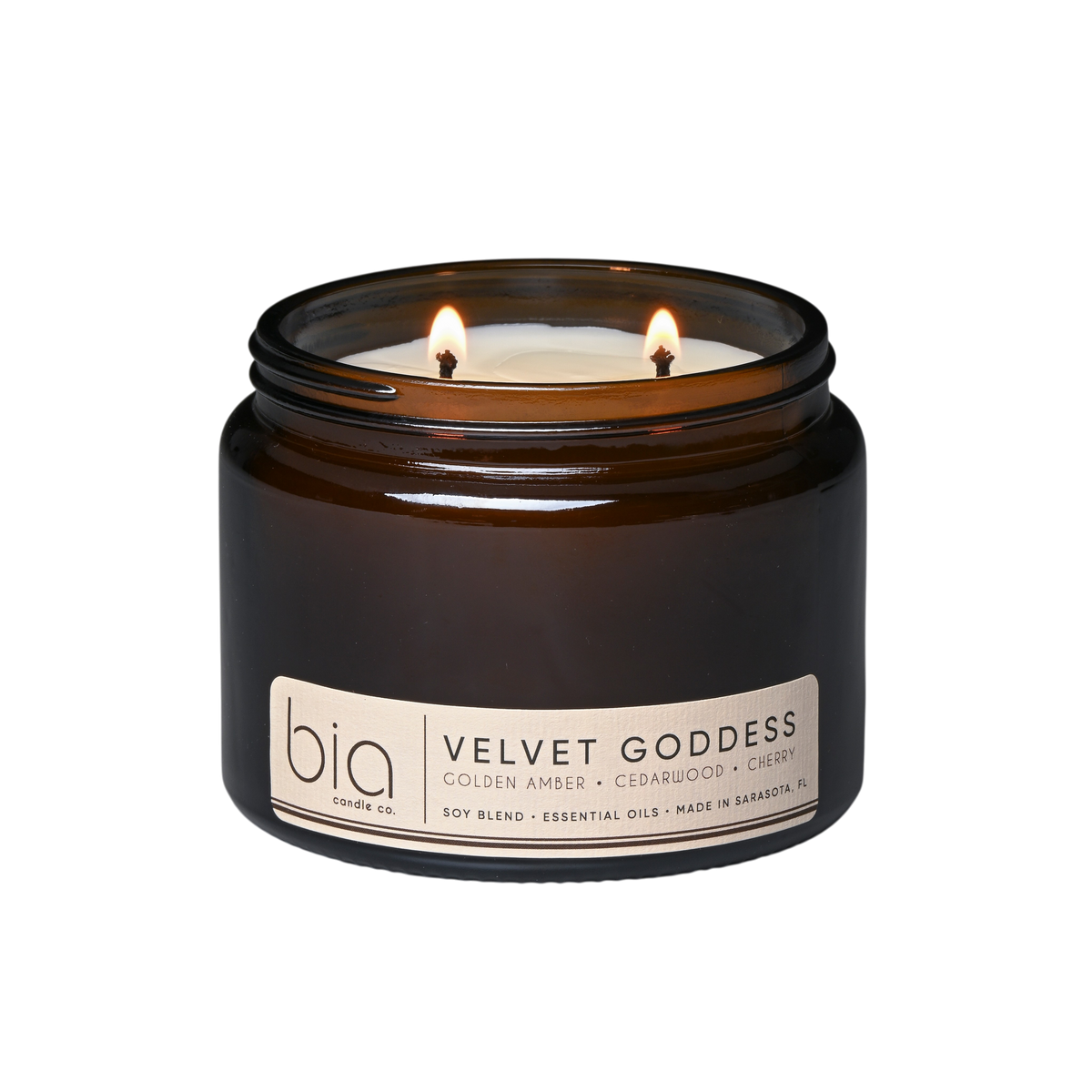 Dark brown glass soy candle jar with two lit wicks and printed front label