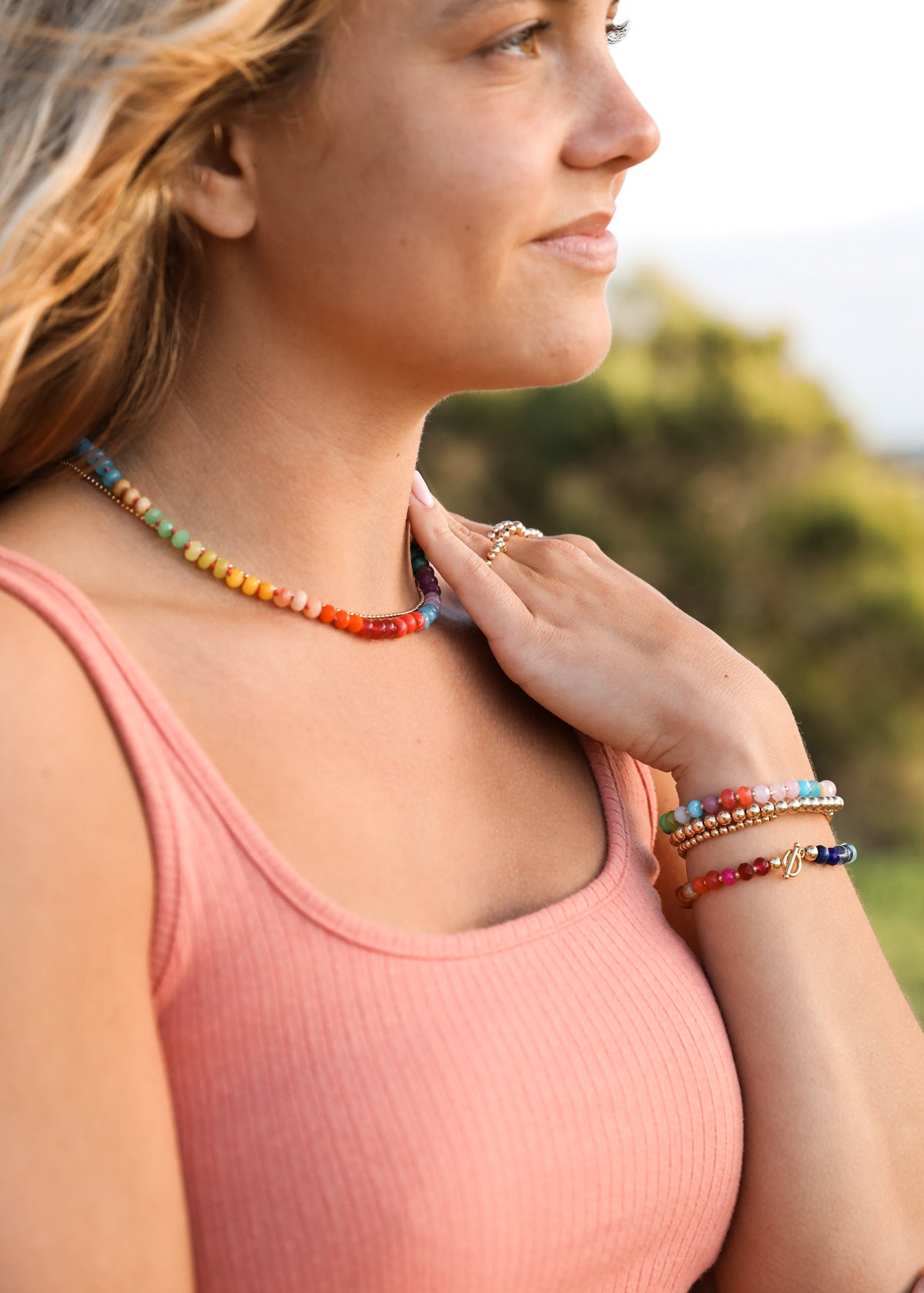 Rainbow gemstone beaded necklace with gold accents, worn at the collar