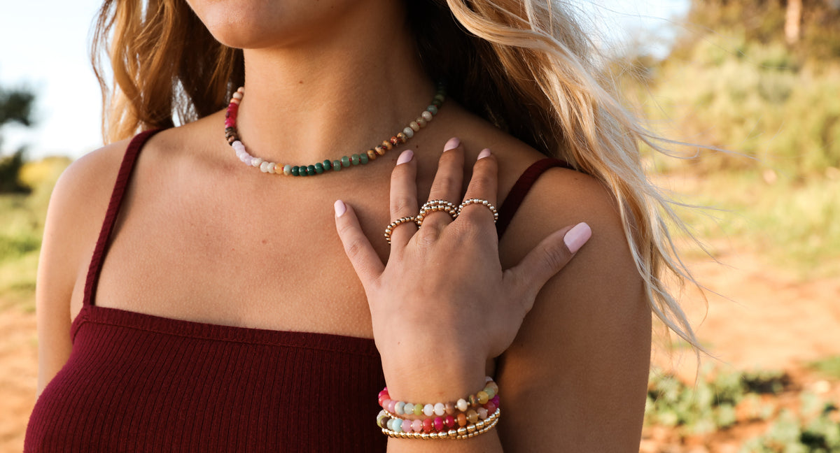 Multicolor gemstone beaded necklace worn with gold toggle clasp, close-up on chest