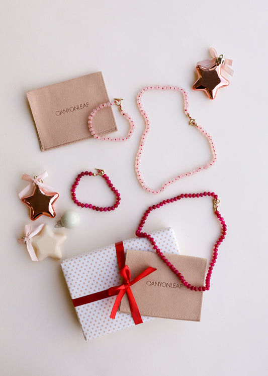 Pink beaded bracelet with gold toggle clasp, styled on gift boxes