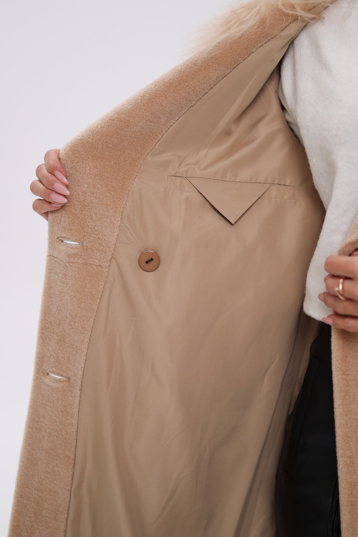 Open coat showing beige lining, inner button, and welt pocket