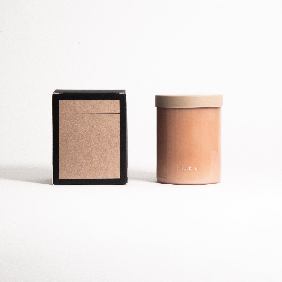 Candle jar beside square black box; candle front shows "Field Kit".