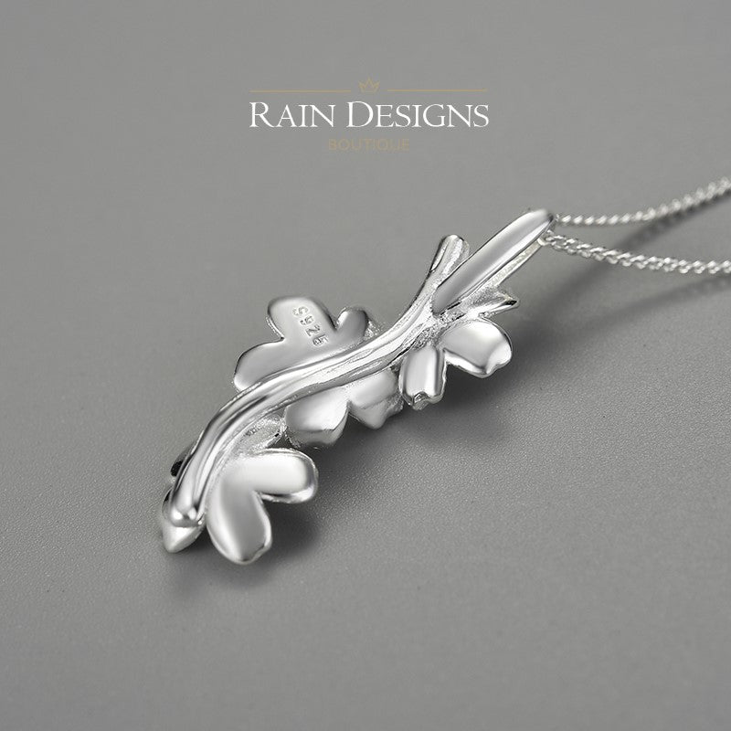 Silver forget-me-not flower necklace pendant with leaf-like stem on a chain.
