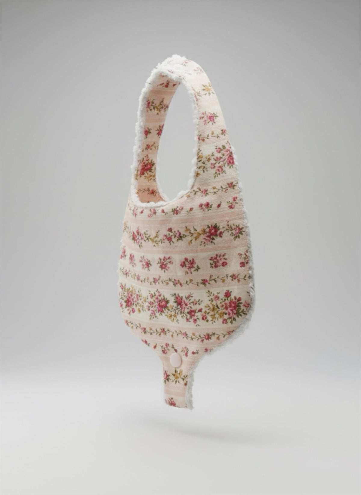 Floral pacifier bib with snap closure, draped pouch shape and pacifier loop.