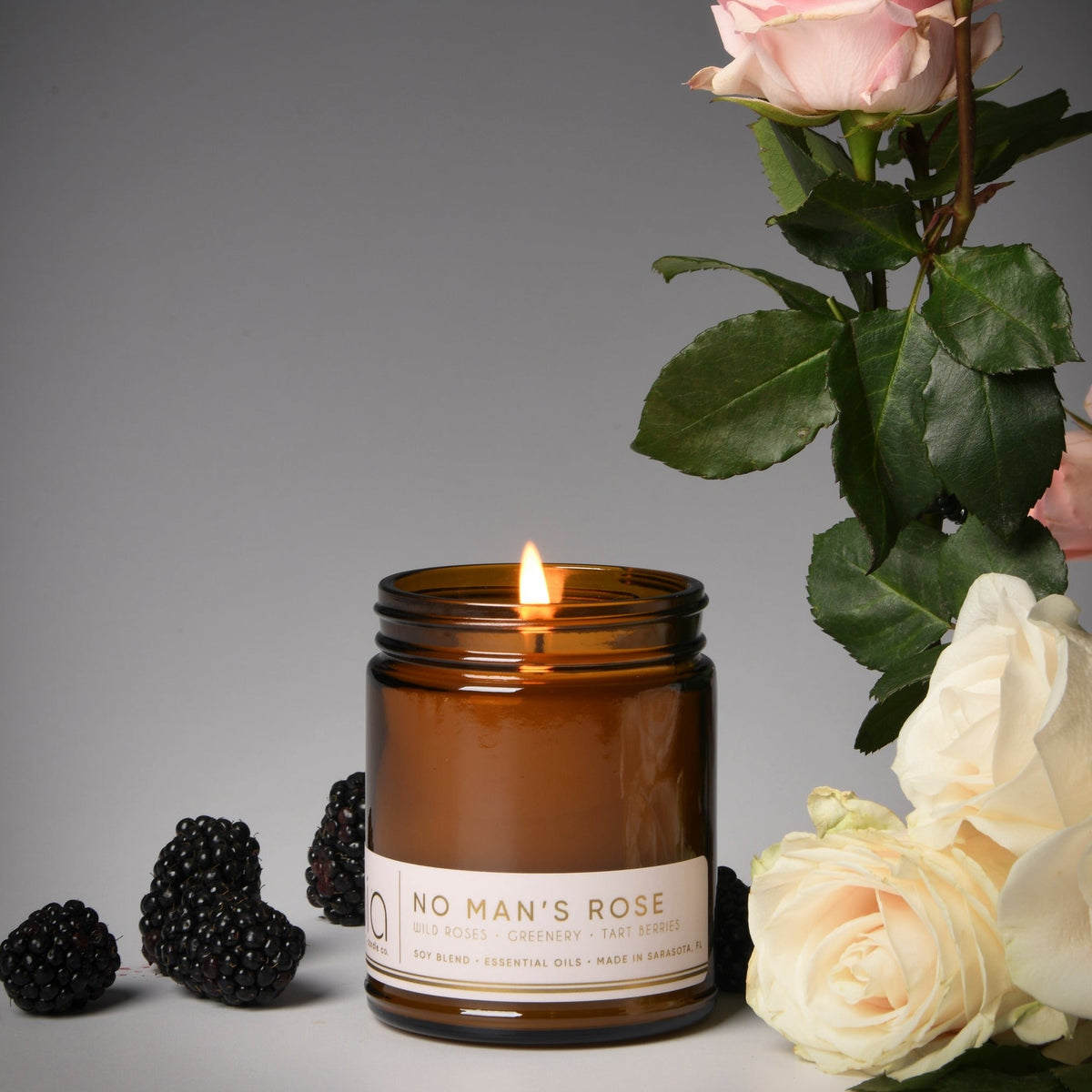 Brown amber soy blend candle jar with lit wick and printed label