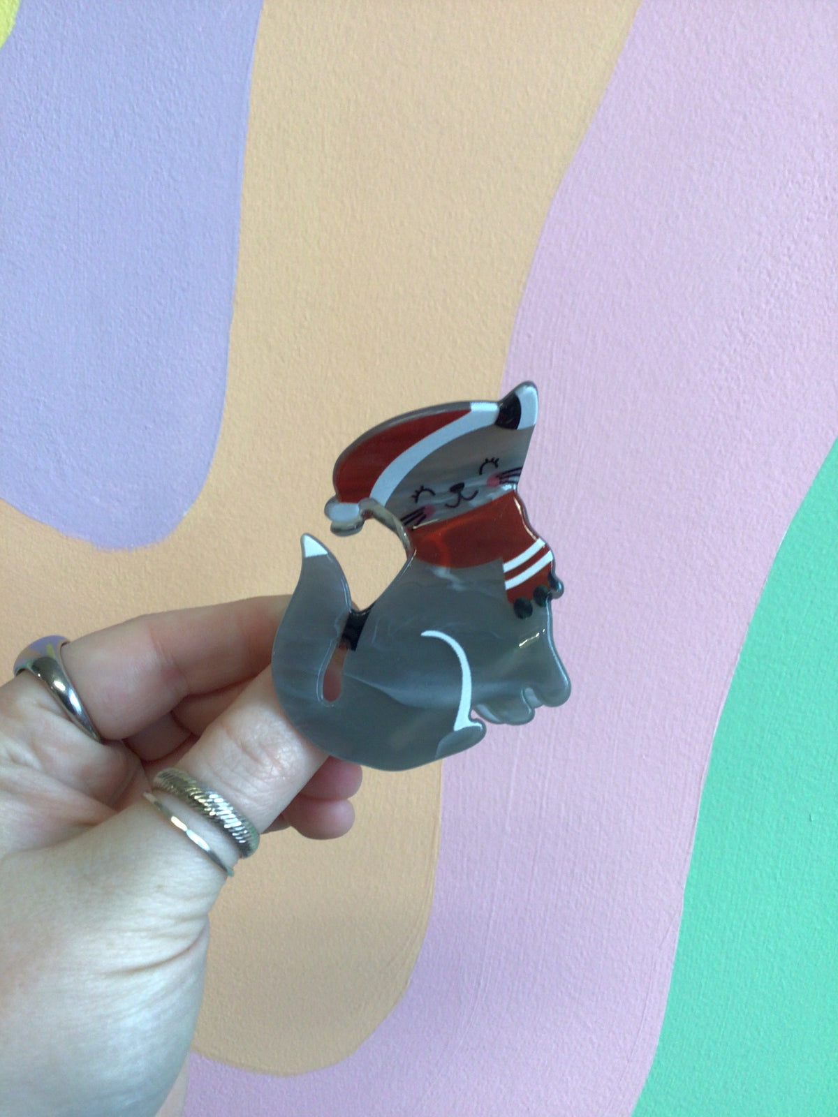 Festive cat hair claw with grey cat figure and red striped hat detail