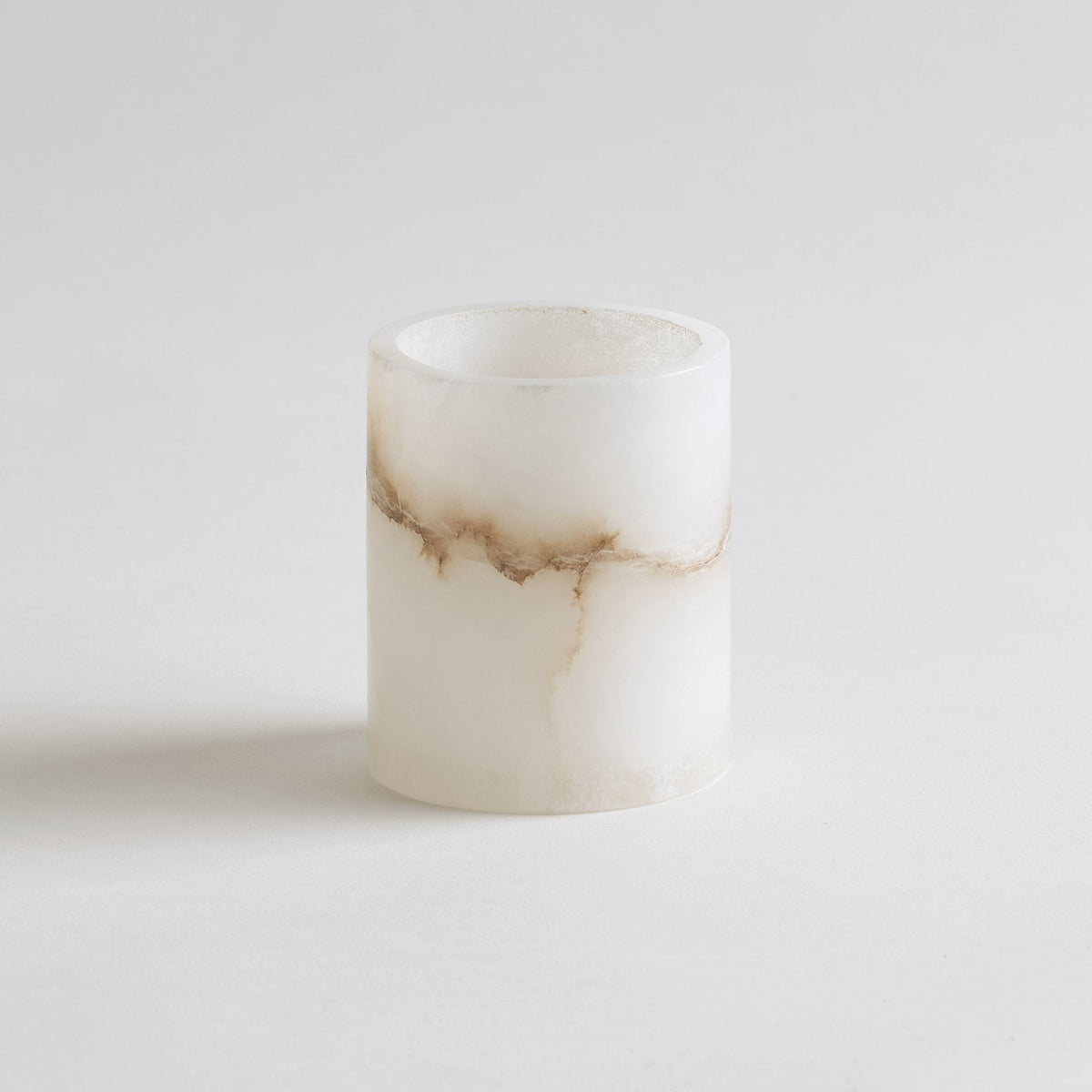 Short alabaster-style votive candle, unlit white cylinder with warm beige veining