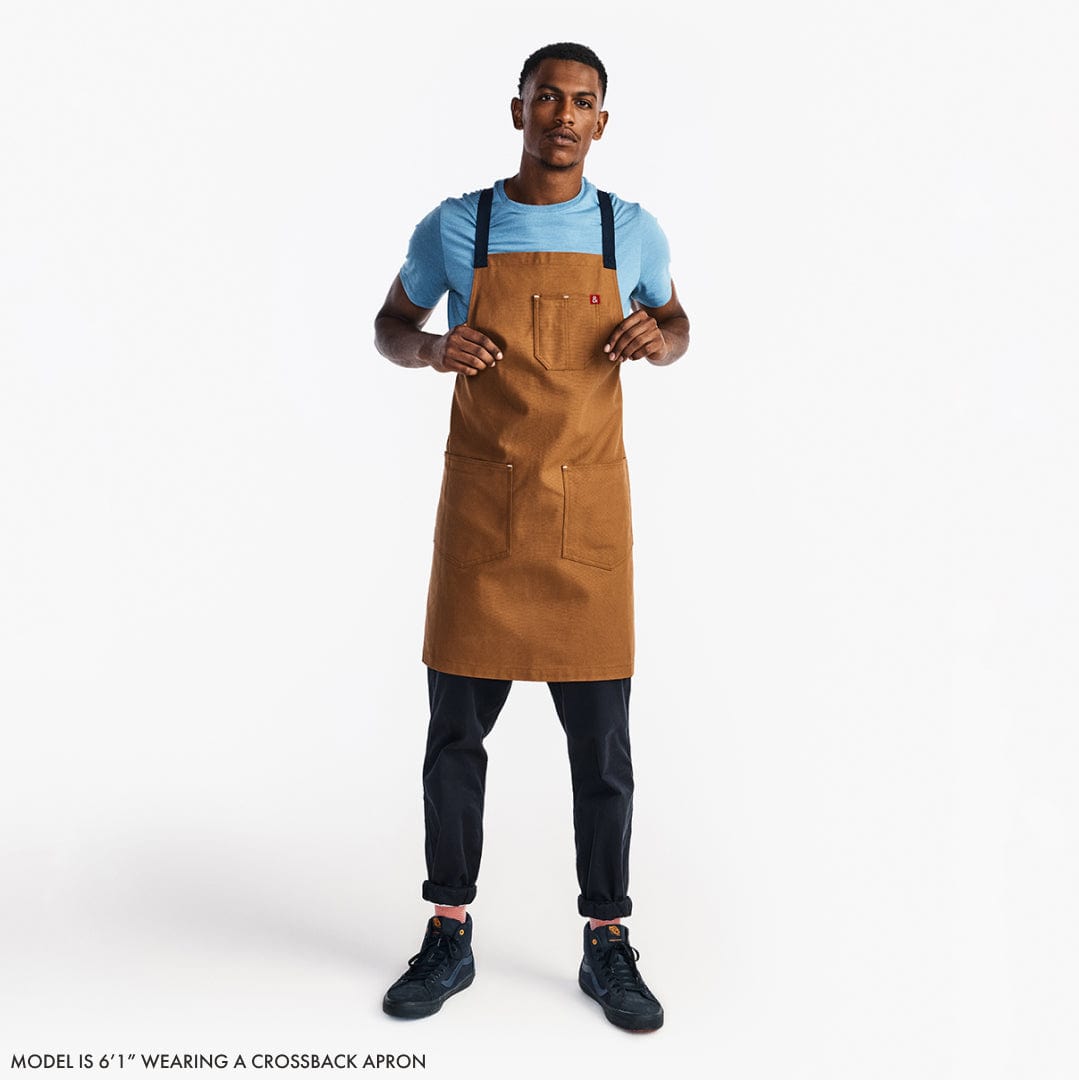 Black floral crossback apron with beige straps on a standing model