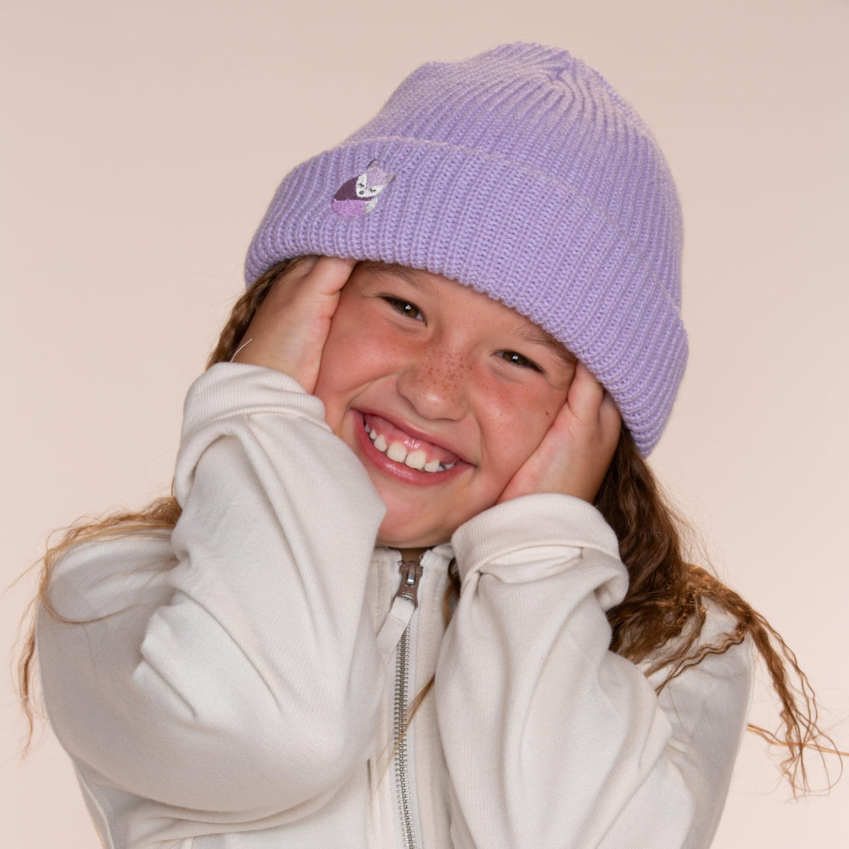 Purple fox-embroidered beanie worn by a child, showing the folded cuff