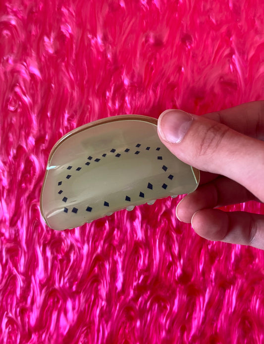 Fruit hair claw with beige top and dark dot pattern, curved base