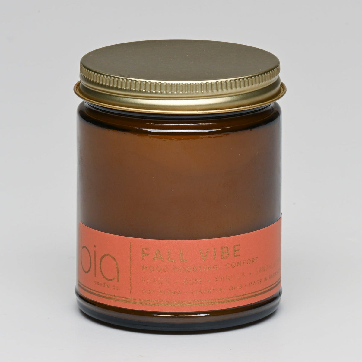 Amber soy candle jar with gold lid top and orange label band on glass