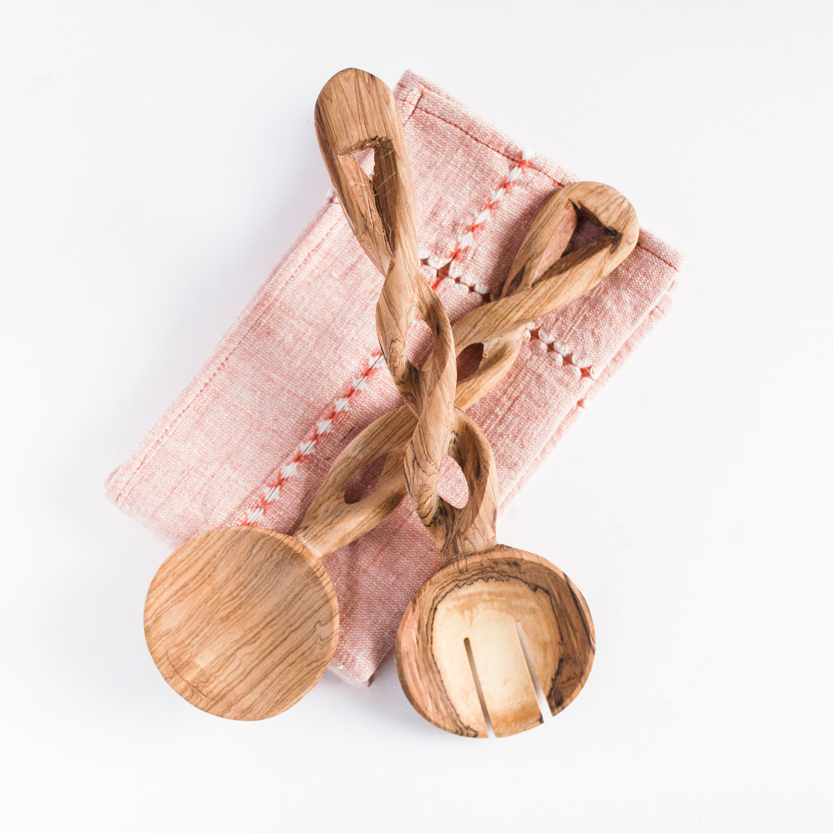 Olive wood spiral serving spoons with round scoops and carved oval cutouts, angled.