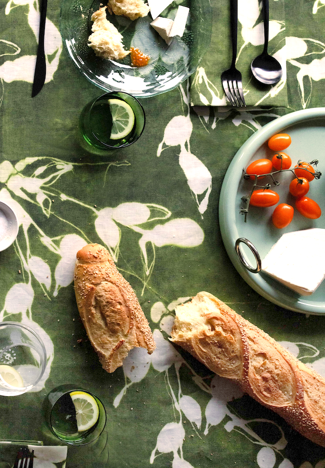 Olive green tablecloth with white botanical leaf pattern, laid on table