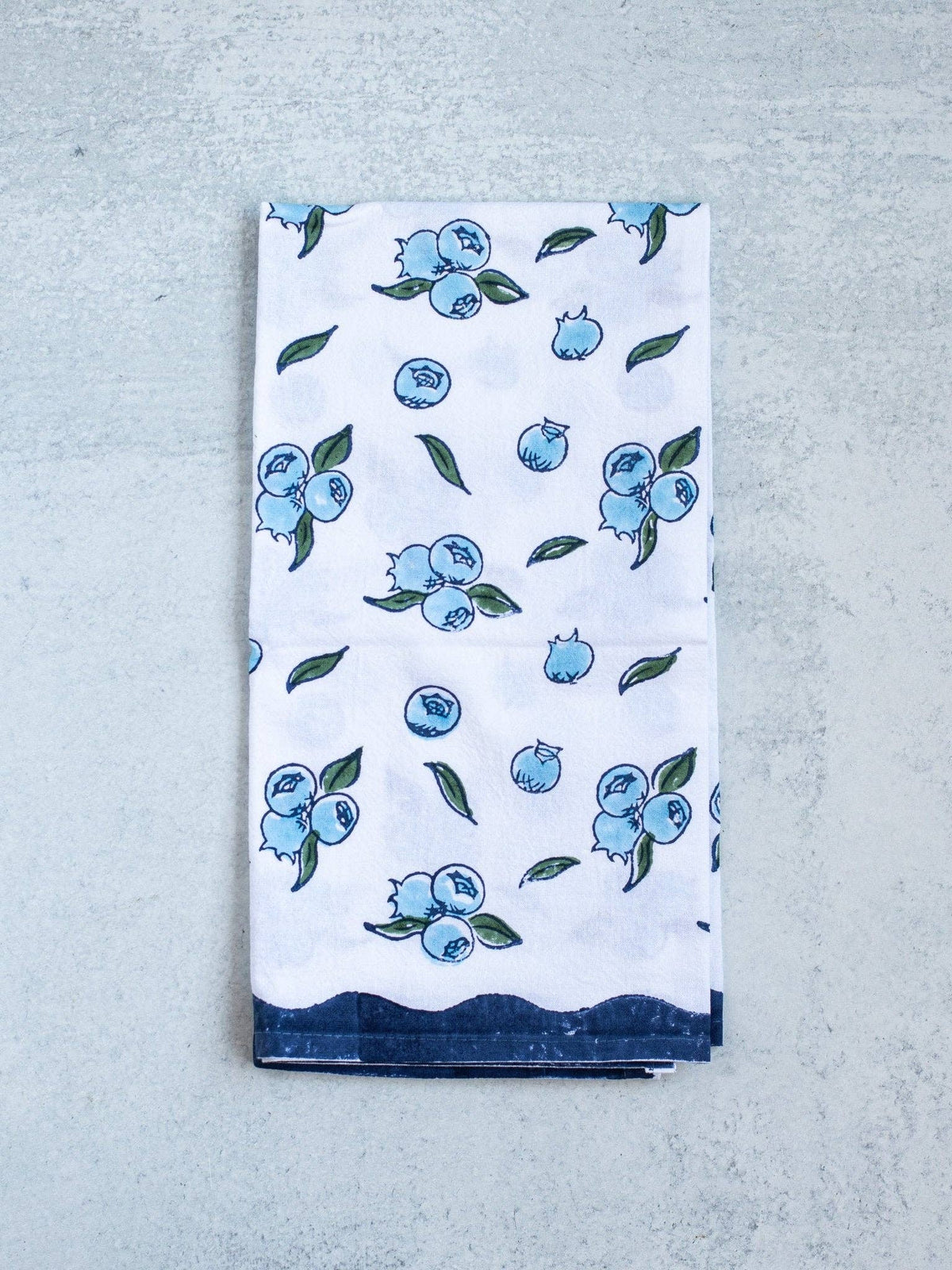 Blueberry tea towel, white with scattered blue berries and green leaves, folded