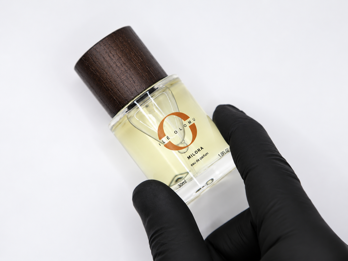 30ml eau de parfum bottle with dark wooden cap in black-gloved hands