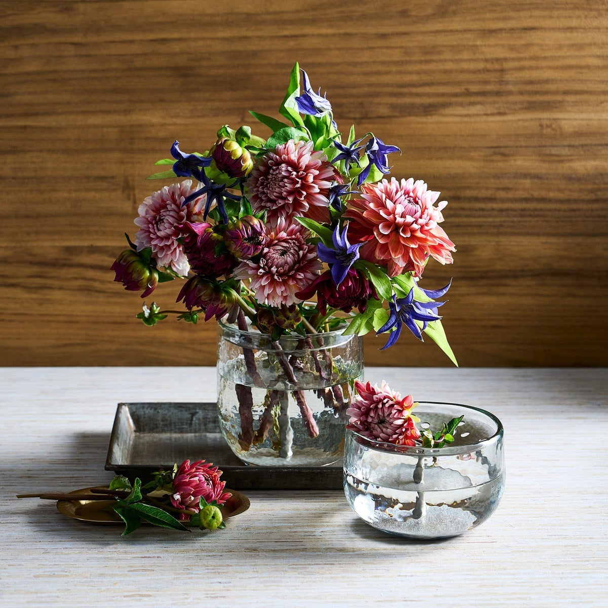 Low glass floral centerpiece with perforated metal flower frog holding red and blue flowers