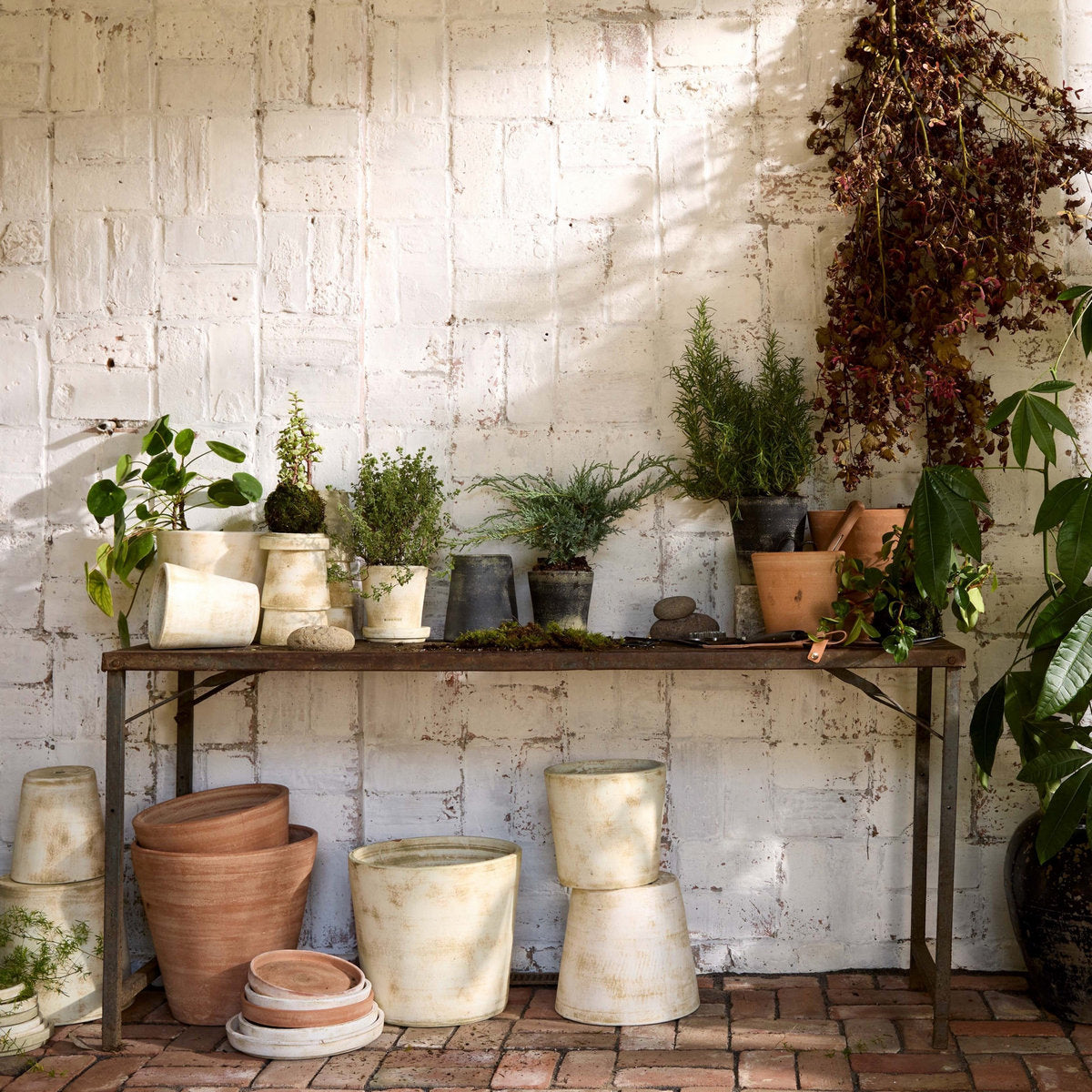 White patina terra-cotta planters on a shelf and stacked on the floor