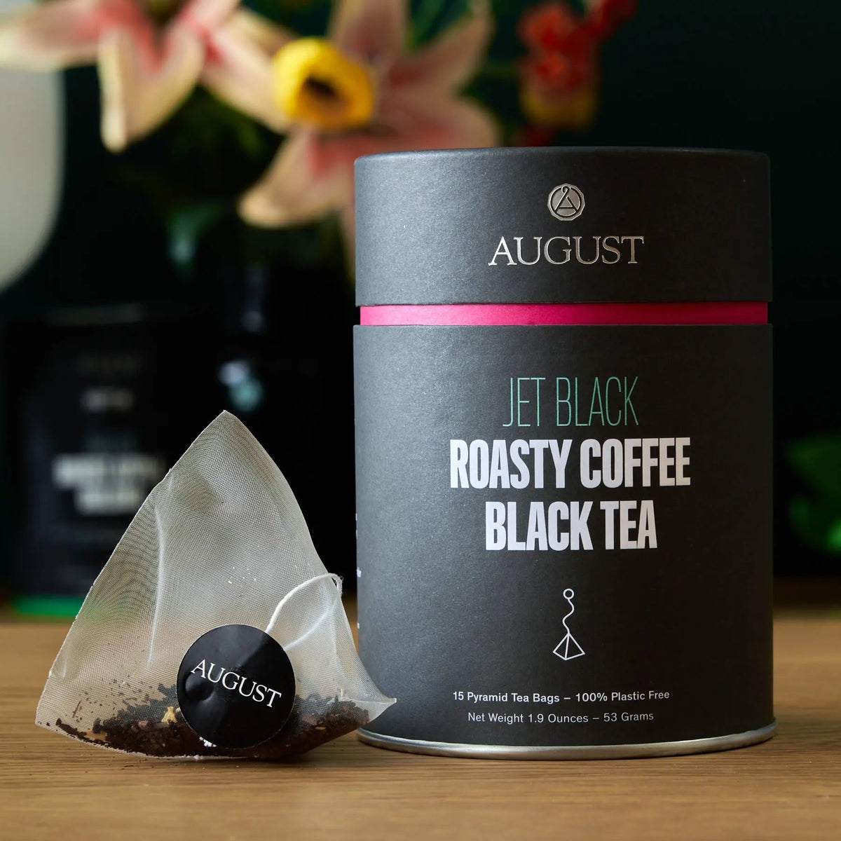Black tea tin beside a pyramid tea bag with an August tag.