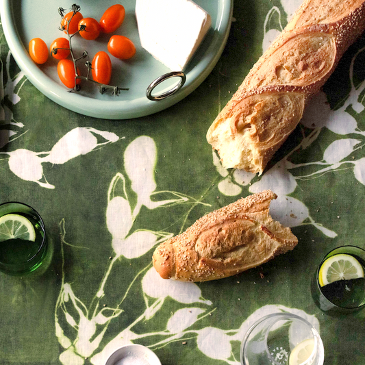 Olive green leaf-print tablecloth with white motifs, top-down on table