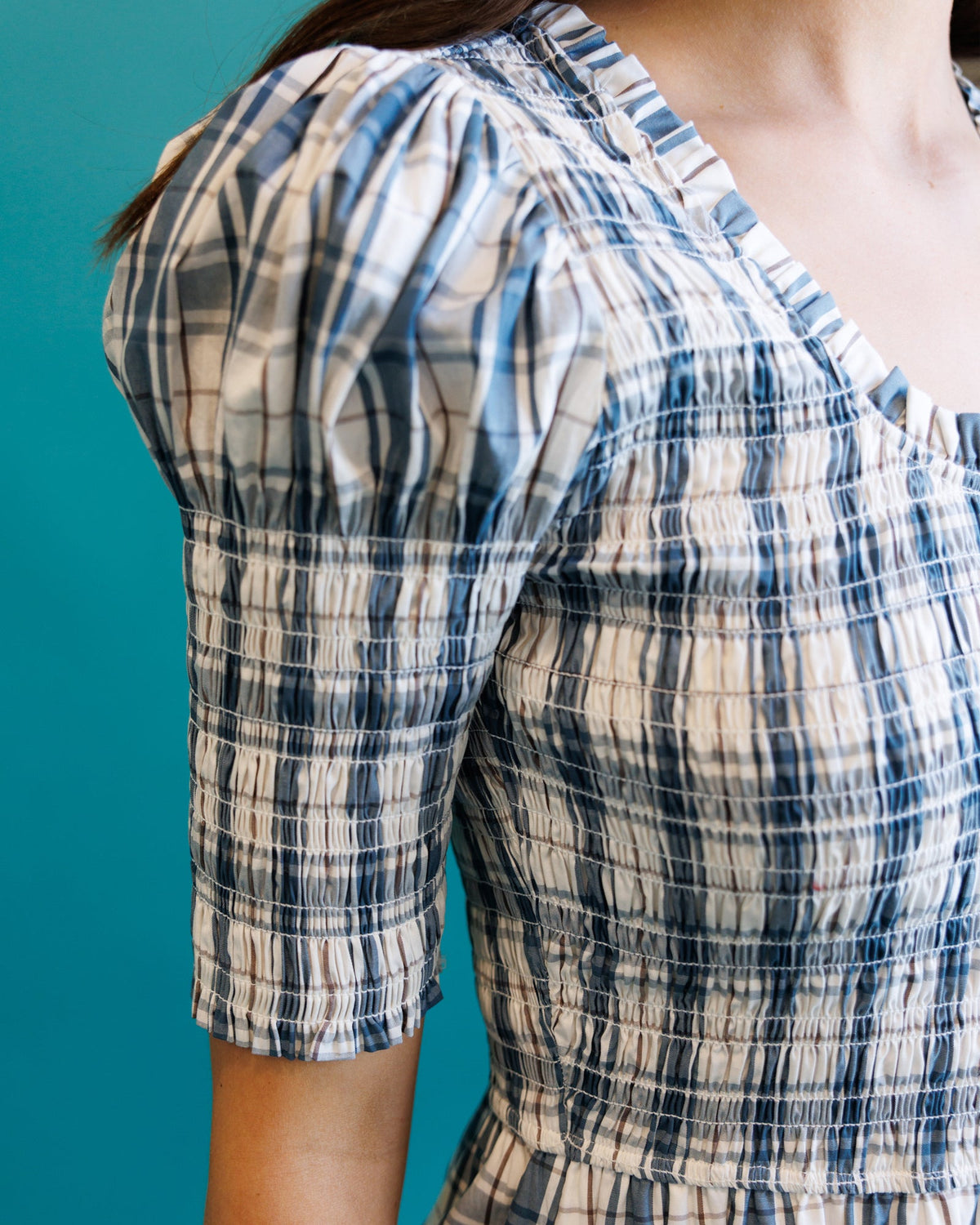 Close-up of cream and blue plaid oxford dress puff sleeve with gathered elastic.