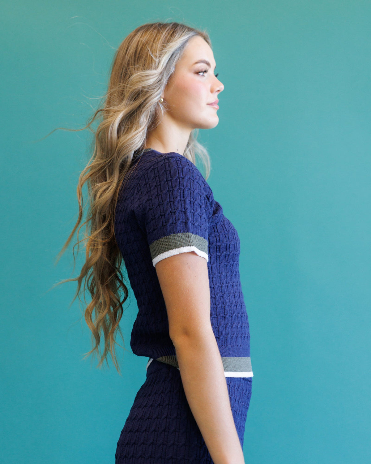 Dark blue cable-knit crew sweater, side view, ribbed cuffs and hem with light trim