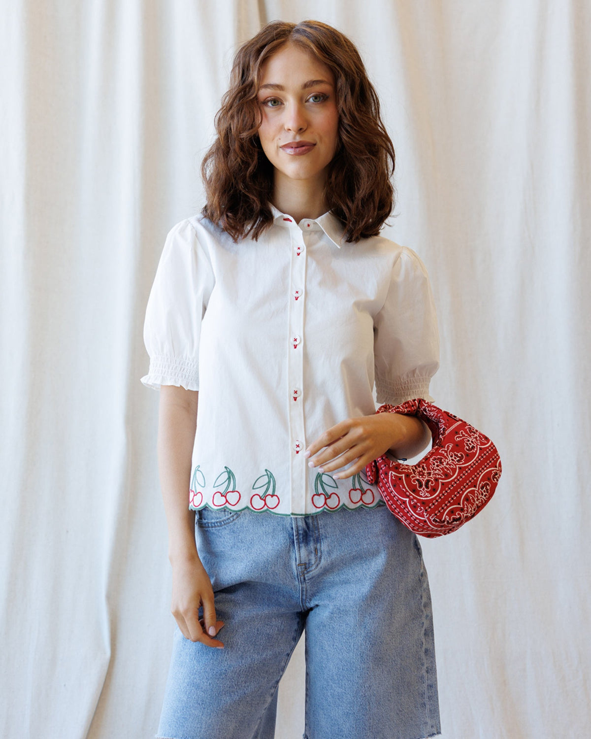 White button-down shirt with puff sleeves, cherry hem embroidery, and red buttons