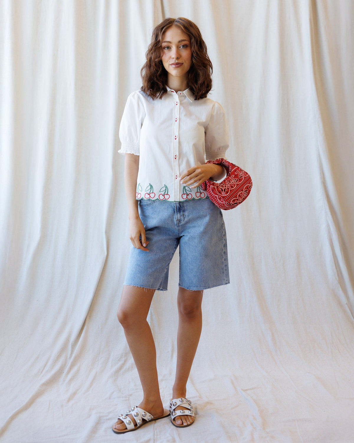 White button-down shirt with cherry hem embroidery, red button placket, and puff sleeves