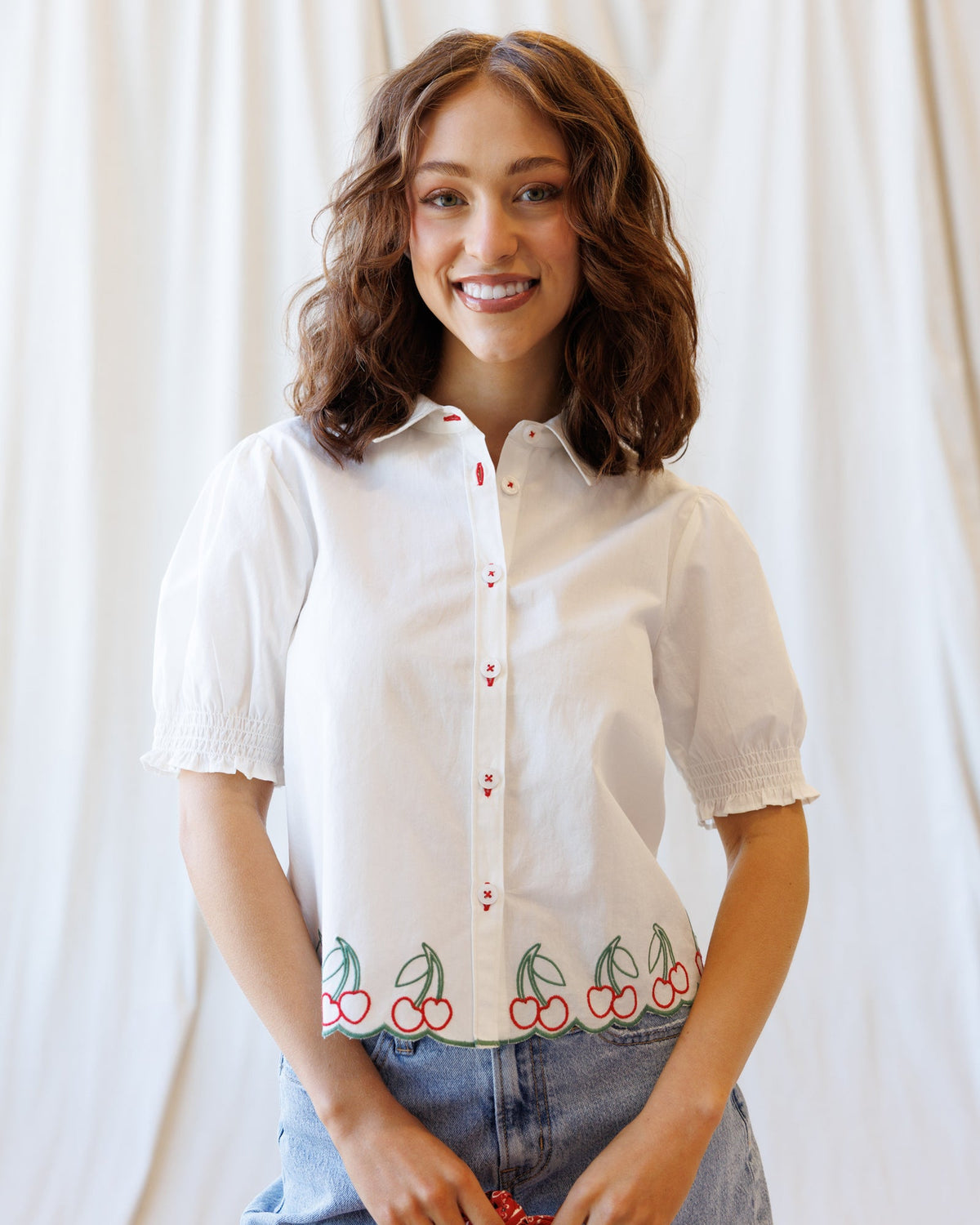 White button-down shirt with cherry hem embroidery and red button placket