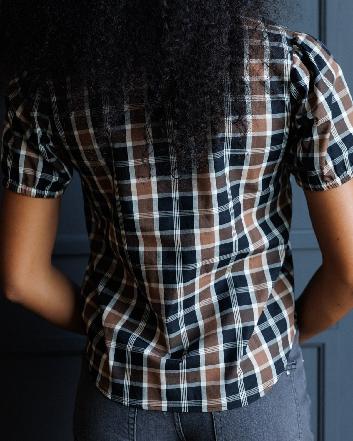 Back/side view of a dark plaid short-sleeve button-down shirt