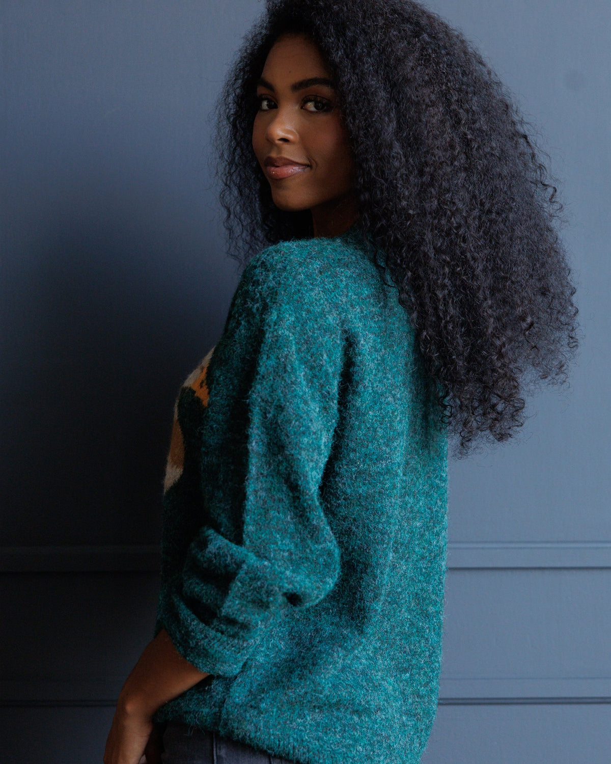 Forest green knit sweater with bird graphic partially visible, long sleeves