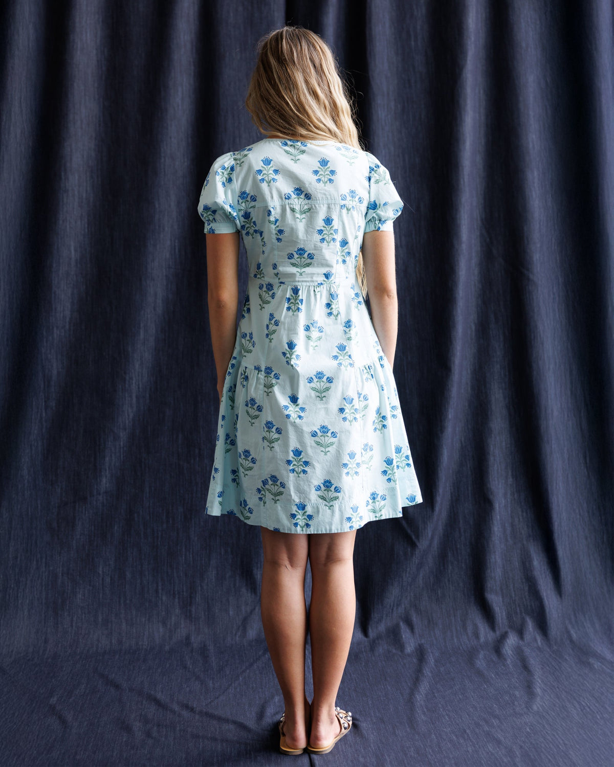 White floral print dress with blue puff sleeves and gathered waist, back view