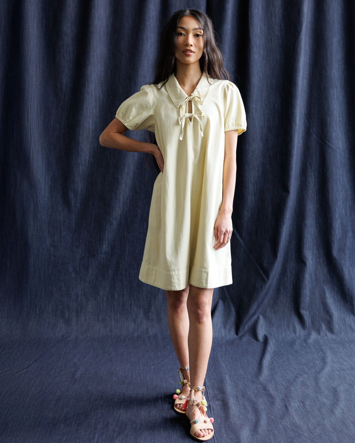 Light yellow denim dress with collared neck ribbon bow and short puff sleeves, front view