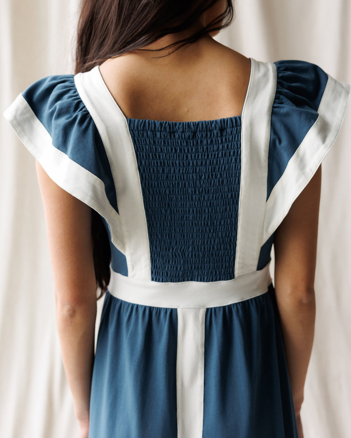 Women’s Block Party dress back detail with smocked bodice and blue panel, white trim
