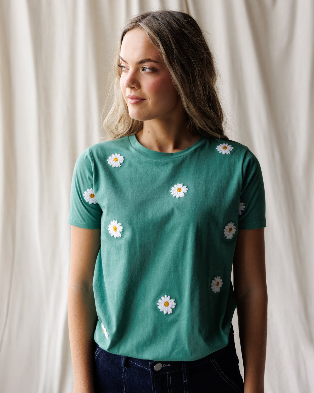 Women's teal crew-neck tee with scattered white daisy embroidery.