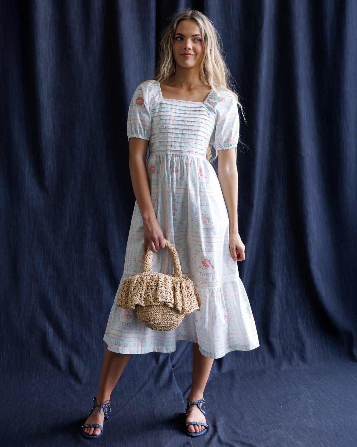 White tiered dress with puff sleeves and square neckline, cross-stitch style print