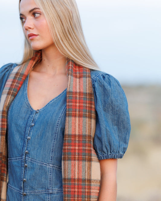Plaid scarf worn at the neck with tan, rust, and blue pattern